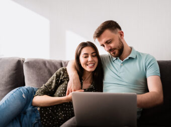 Man and woman sitting on sofa with a laptop
